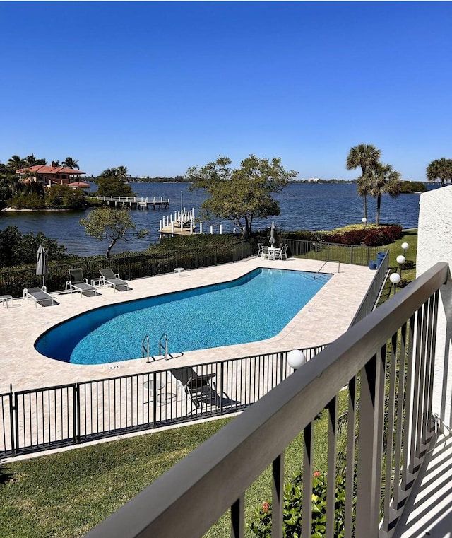 community pool featuring a water view, fence, and a patio