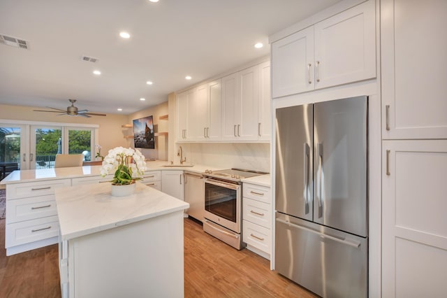 kitchen with appliances with stainless steel finishes, white cabinets, visible vents, and a peninsula