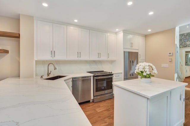 kitchen with a sink, white cabinetry, light wood-style floors, appliances with stainless steel finishes, and open shelves