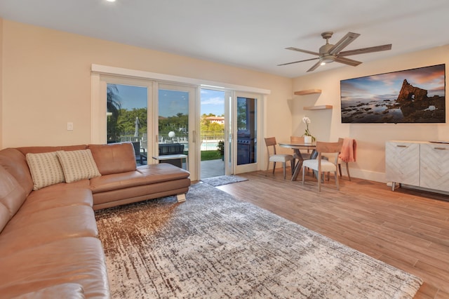 living room featuring a ceiling fan, baseboards, and wood finished floors