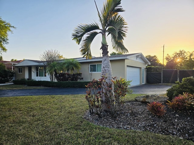 ranch-style house featuring stucco siding, driveway, fence, a front yard, and a garage