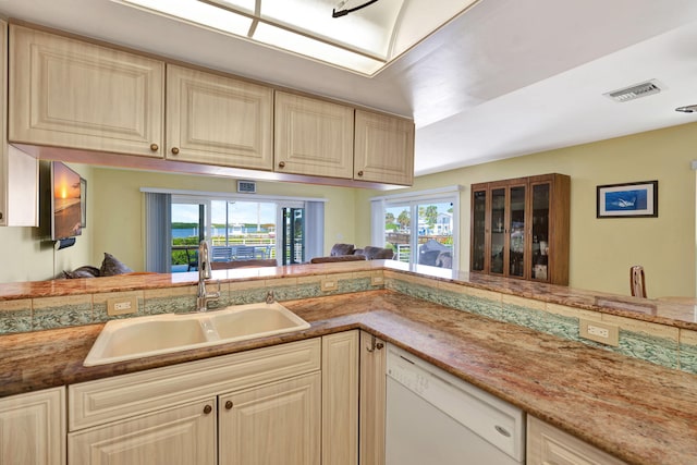 kitchen featuring visible vents, white dishwasher, and a sink