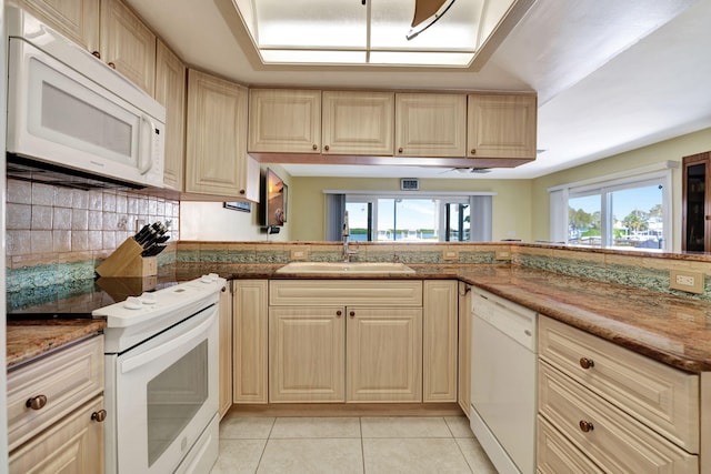 kitchen featuring light tile patterned floors, white appliances, a sink, and decorative backsplash