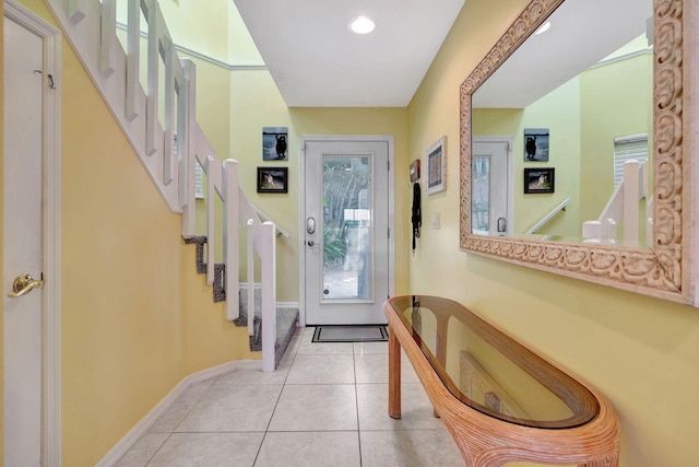 doorway featuring light tile patterned floors, stairway, and baseboards