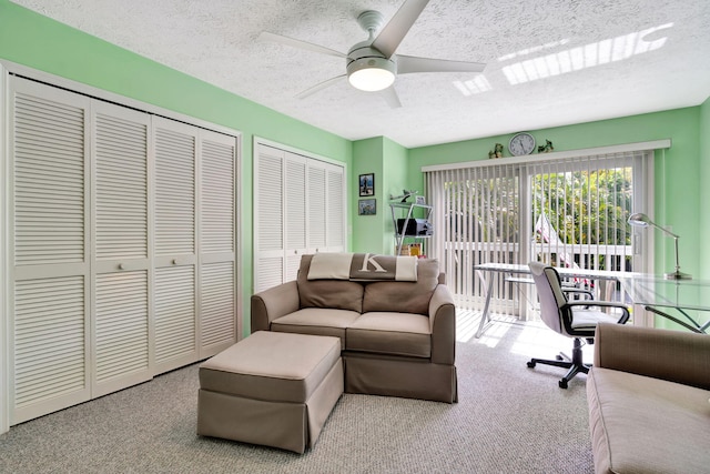 carpeted living room featuring ceiling fan and a textured ceiling