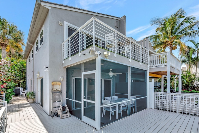 back of property featuring a deck, cooling unit, a sunroom, and stucco siding