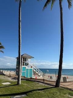 view of playground with a yard, a water view, and a view of the beach