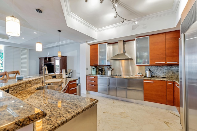 kitchen featuring a sink, a tray ceiling, wall chimney exhaust hood, brown cabinetry, and modern cabinets