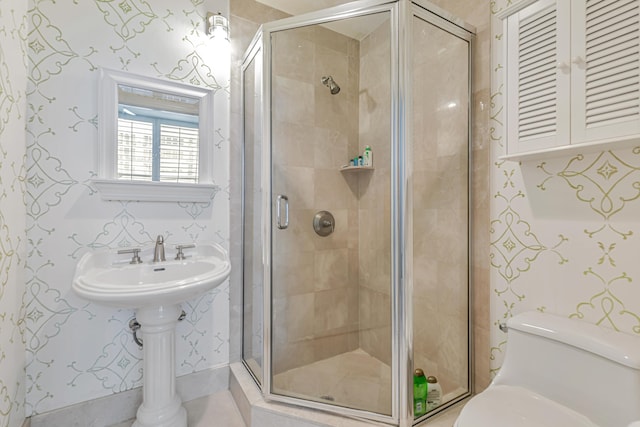 bathroom with a stall shower, toilet, and wallpapered walls