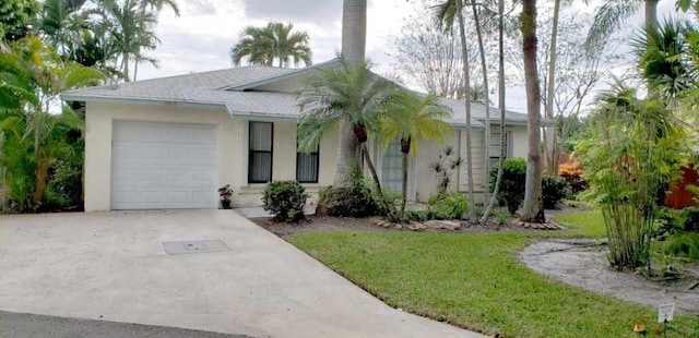 ranch-style house featuring an attached garage, a shingled roof, driveway, stucco siding, and a front yard