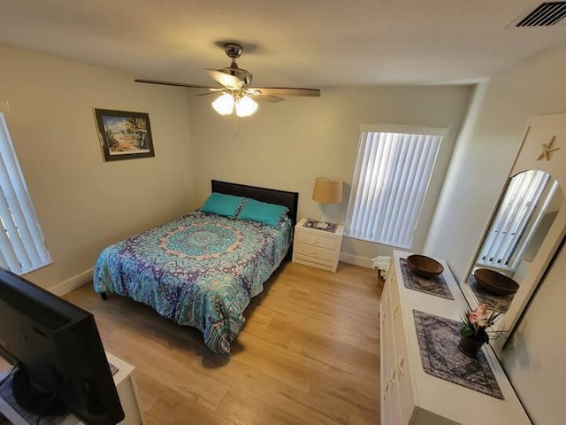 bedroom featuring baseboards, a ceiling fan, visible vents, and light wood-style floors