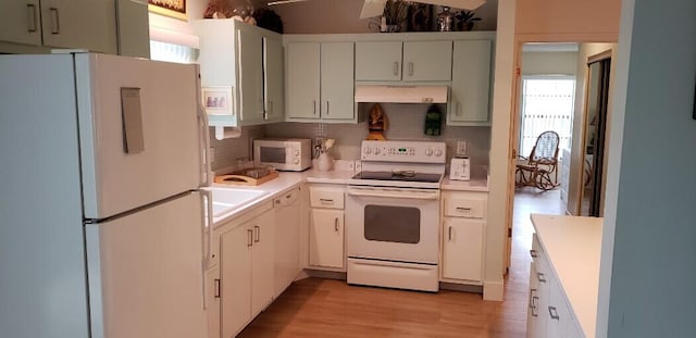 kitchen with white appliances, light countertops, under cabinet range hood, and backsplash