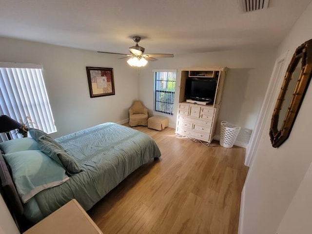 bedroom with baseboards, light wood finished floors, visible vents, and a ceiling fan