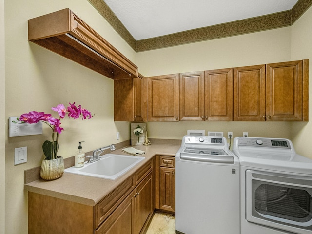 clothes washing area with a sink, cabinet space, and washer and dryer