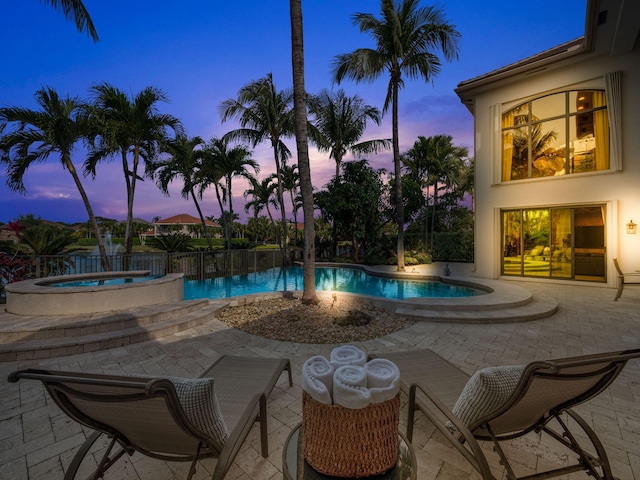 pool at dusk featuring a fenced in pool, a patio, and an in ground hot tub