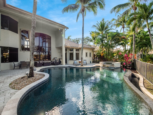 view of swimming pool featuring a patio area, a pool with connected hot tub, fence, and an outdoor hangout area