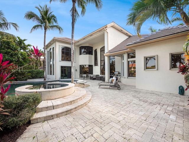 rear view of house featuring an outdoor living space, a patio, and stucco siding