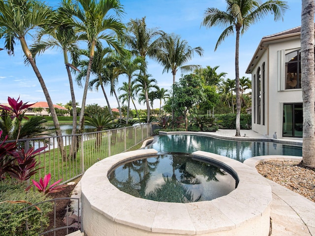 view of pool featuring a pool with connected hot tub and fence