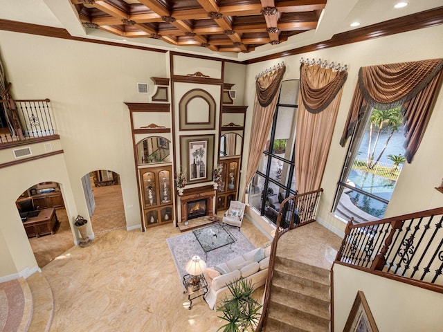 sitting room with arched walkways, a lit fireplace, ornamental molding, and coffered ceiling