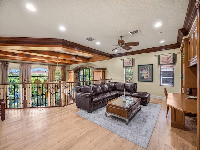 living room with a wealth of natural light, a textured ceiling, visible vents, and wood finished floors