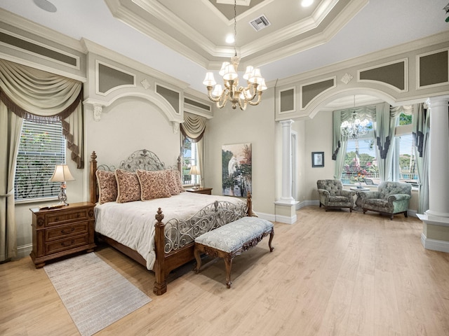 bedroom with light wood-style floors, a raised ceiling, decorative columns, and an inviting chandelier