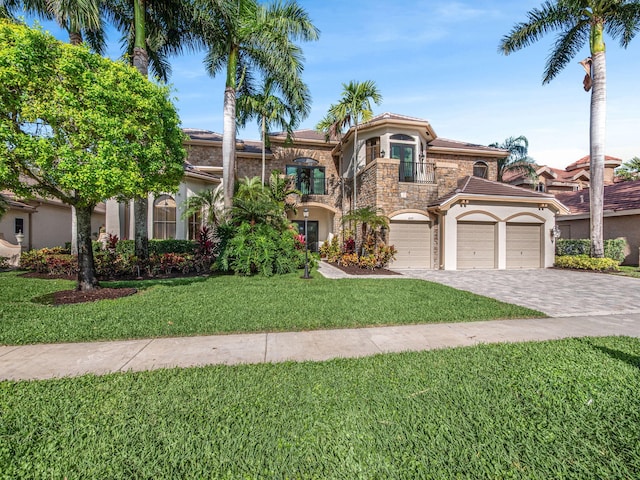 mediterranean / spanish-style house featuring decorative driveway, stucco siding, a balcony, stone siding, and a front lawn