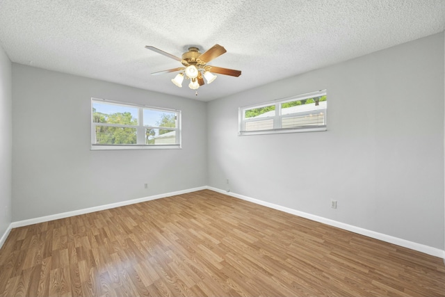 empty room with a ceiling fan, light wood-type flooring, a textured ceiling, and baseboards