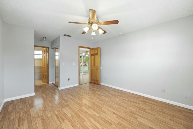 unfurnished room featuring baseboards, visible vents, ceiling fan, a textured ceiling, and light wood-type flooring