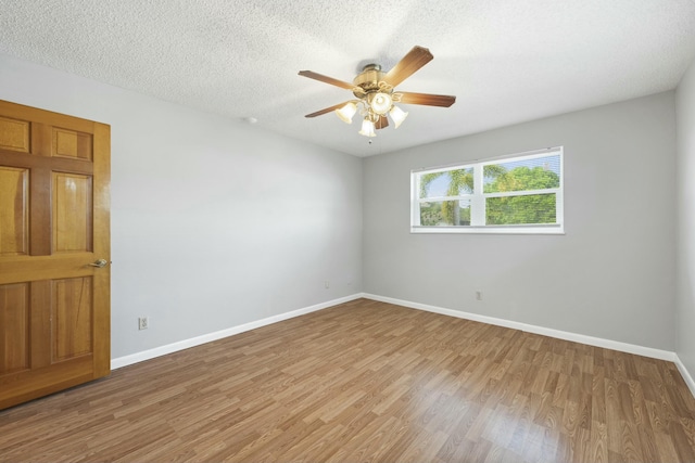 empty room with a textured ceiling, light wood-style flooring, and baseboards