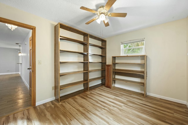 interior space featuring ceiling fan with notable chandelier and wood finished floors