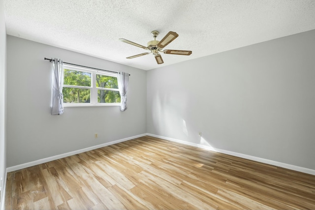 empty room with a textured ceiling, ceiling fan, light wood-style flooring, and baseboards