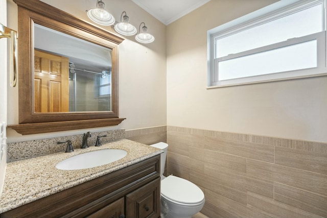 full bath featuring toilet, vanity, tile walls, a shower, and wainscoting