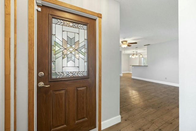 entryway featuring baseboards, dark wood-type flooring, and ceiling fan with notable chandelier