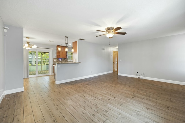 unfurnished living room with visible vents, baseboards, wood finished floors, and ceiling fan with notable chandelier