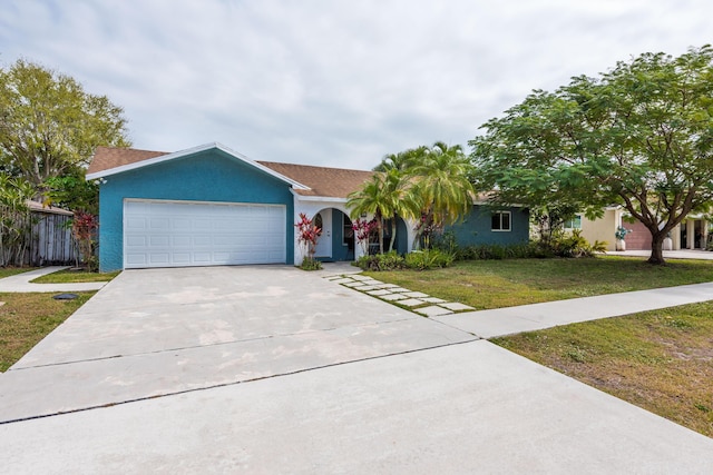 view of front of home featuring a garage, concrete driveway, a front lawn, and stucco siding