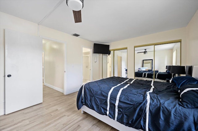 bedroom featuring light wood-type flooring, visible vents, baseboards, and two closets