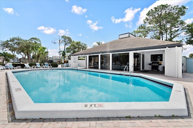 community pool with fence, an outdoor structure, a patio, and area for grilling