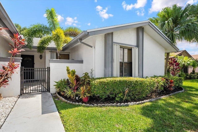 exterior space with a yard, a gate, fence, and stucco siding