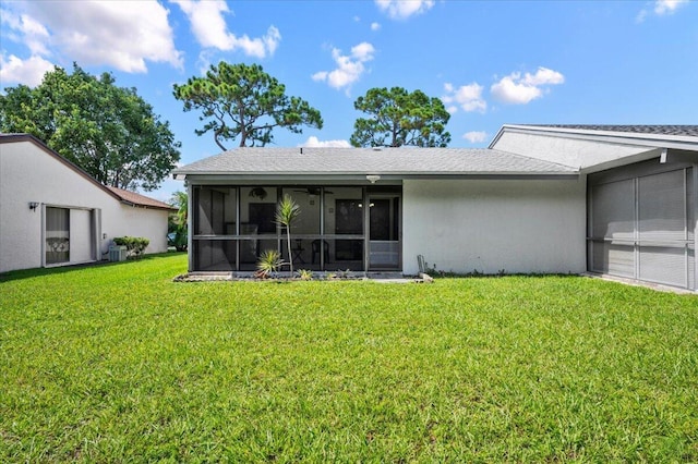 rear view of house with a sunroom, stucco siding, and a yard