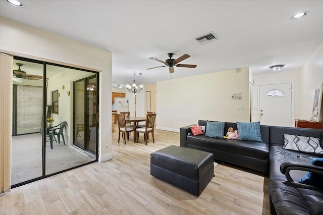 living room featuring light wood finished floors, visible vents, and ceiling fan with notable chandelier