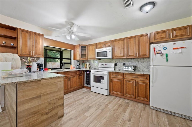 kitchen featuring white appliances, beverage cooler, visible vents, brown cabinets, and a peninsula