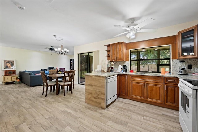 kitchen with white appliances, brown cabinets, backsplash, and ceiling fan with notable chandelier