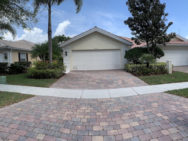 single story home with stucco siding, a tile roof, and decorative driveway