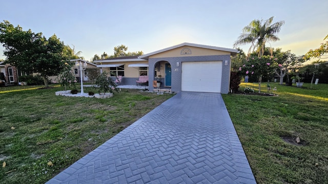 ranch-style house with a garage, a front lawn, decorative driveway, and brick siding