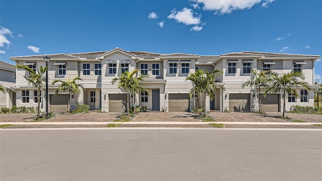 multi unit property featuring a garage, driveway, and stucco siding