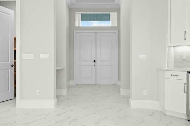 foyer with marble finish floor, baseboards, and ornamental molding