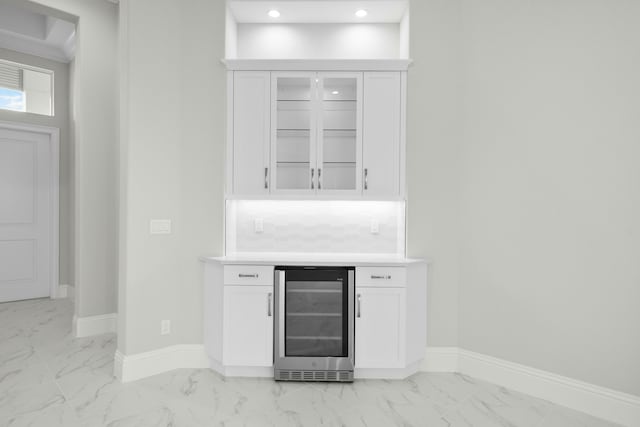 bar featuring beverage cooler, marble finish floor, and baseboards