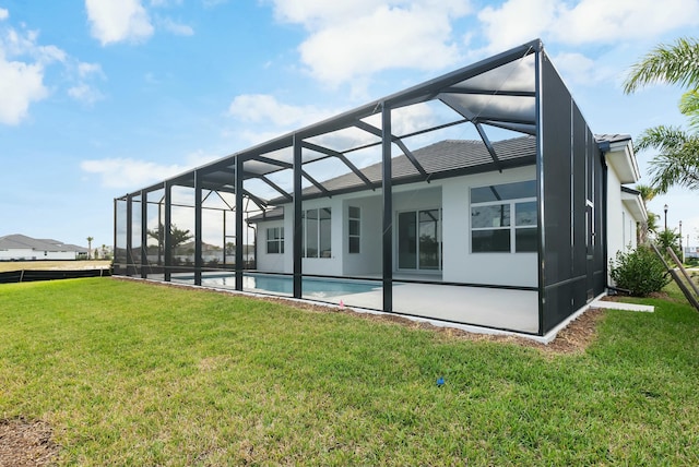 back of house featuring glass enclosure, a lawn, a patio area, and an outdoor pool