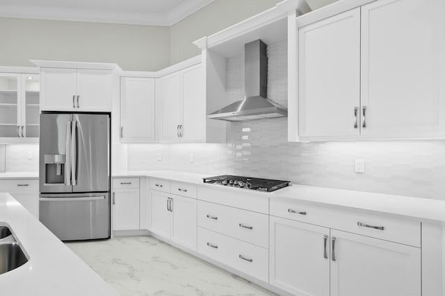 kitchen featuring marble finish floor, crown molding, light countertops, appliances with stainless steel finishes, and wall chimney range hood