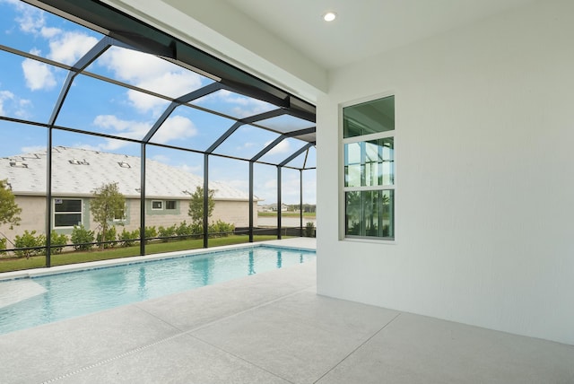 pool featuring glass enclosure and a patio area